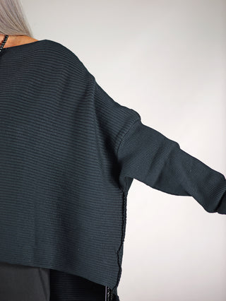 Philomena Ripp Pulli FEAT schwarz: Person trägt einen schwarzen, leichten, boxy geschnittenen Ripp-Pullover, ideal für den Alltag. Der Pullover besteht aus Modal, Polyester und Polyamid.