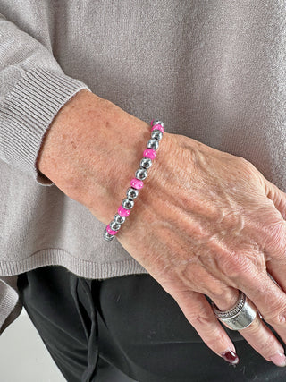 Glam & Rock Armband Edelstahl rosa, getragen an einem Handgelenk. Das elastische Armband kombiniert Edelstahl mit rosa Edelsteinen und hat einen Durchmesser von etwa 5 mm.