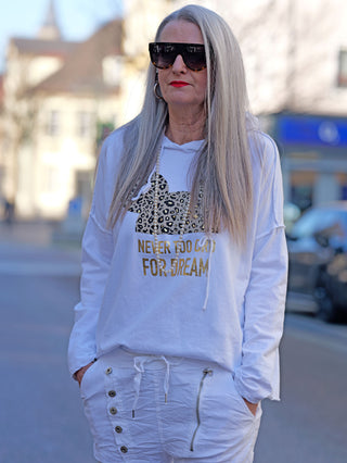 Frau mit langen grauen Haaren trägt eine Sonnenbrille und das OFF#DLY Hoody Tee Dream weiß mit Goldprint, gerade Passform, aus Baumwolle-Elastan-Mischung, street fashion inspiriert.