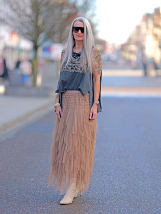 Eine Frau trägt das OFF#DLY Shirt Luise grau mit großem Rundhals- und weitem Ärmelausschnitt, kombiniert mit einem rüschigen Rock und Sonnenbrille, im Street-Fashion-Stil.