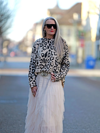 Frau trägt OFF#DLY Longsleeve Clara beige/black mit Rundhals und Animalprint, leicht oversized. Gekleidet mit Sonnenbrille, lässiger Straßenmode-Stil.