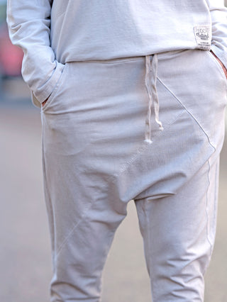 Person trägt die OFF#DLY Jogger Pant Tina beige, eine lässige Baggy-Joggerhose mit Gummibund und Kordelzug, seitlichen Einschubtaschen und hinten Taschen, aus leichter Sweat-Qualität.