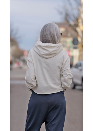 Frau mit grauen Haaren trägt OFF#DLY Hoody Selma beige, leichtes Kapuzensweatshirt mit boxy Passform. Perfekt für lässige Street-Styles.