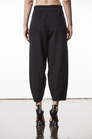 Thom Krom Hose WST 414 black: Person trägt locker sitzende, leicht ballonförmige Leinenhose mit schwarzem Design, kombiniert mit eleganten Absätzen. Der Fokus liegt auf den strukturierten Beinen und der modischen Passform.