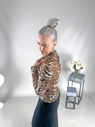 Frau in einem OFF#DLY Longsleeve Tiger beige/black mit Katzenprint und Strasssteinen, stehend vor einem weißen Hintergrund.