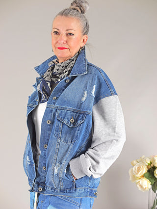 OFF#DLY Denim Jacket Conny midblue/grey: Frau mit Händen in den Taschen trägt Oversize-Jeansjacke mit Sweatärmeln. Modell ist 172 cm groß, trägt Größe S/M.