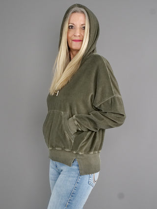 Frau trägt True Religion Hoodie Cold Dye Leaf, leicht oversize im Boxy-Look mit breiten Bündchen und Kängurutasche, aus kuscheligem Frottee-Material.